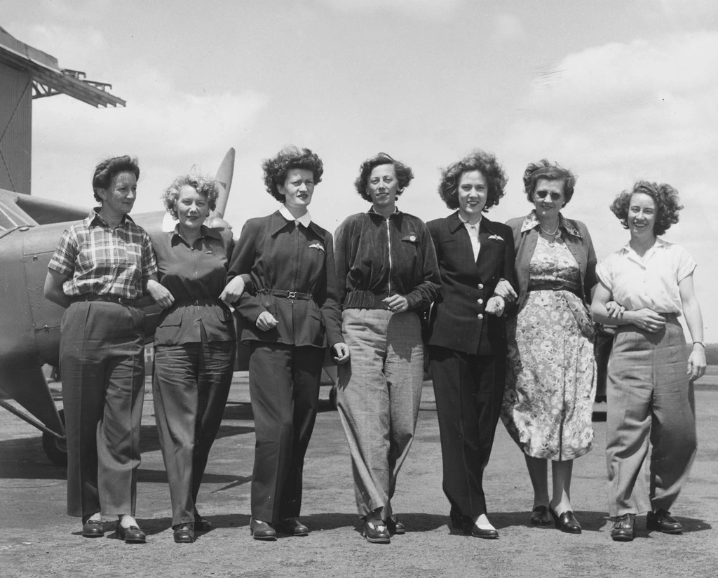 a group of women standing in front of the plane